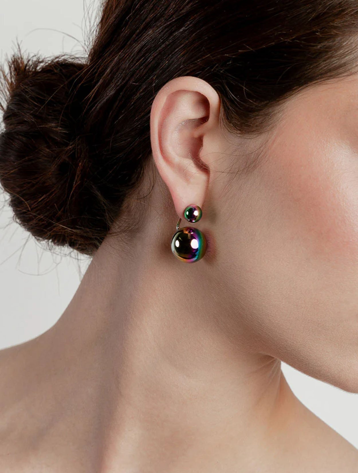 Aretes maxi Saka en acrílico holográfico con baño de oro para mujer – Sofía Llanos | Casa Precis, Concept Store. Segundo plano.