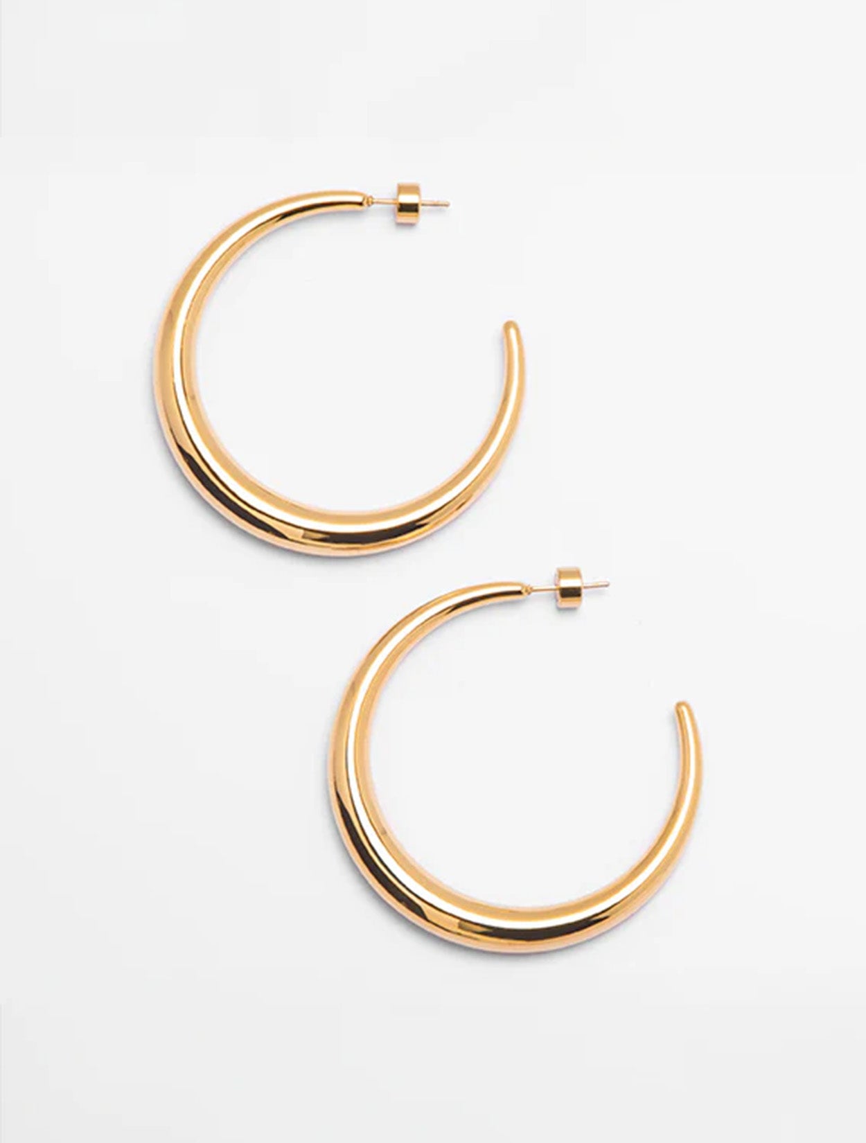Aretes tipo candonga Afti Hoops en baño de oro con diseño orgánico para mujer – Sofía Llanos | Casa Precis, Concept Store. Primer plano.