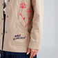 Chaqueta tipo parka caqui con bordado Aquí Florezco para mujer – Juliana Sanchez | Casa Precis, Concept Store. Segundo plano.