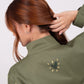 Chaqueta tipo parka verde militar con bordado Fuego para mujer – Juliana Sanchez | Casa Precis, Concept Store. Segundo plano.
