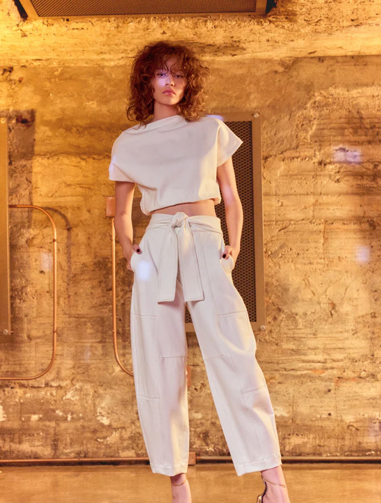 Top Luxe Rebel de Nord & Sud en color negro con detalles de ojales metálicos decorativos y fit estructurado – Moda colombiana vanguardista | Casa Precis, Concept Store. Segundo plano.
